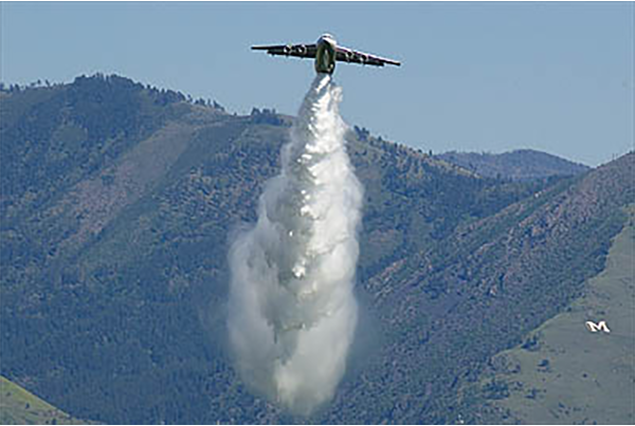Avro RJ85 air tanker releasing retardant over forested hills